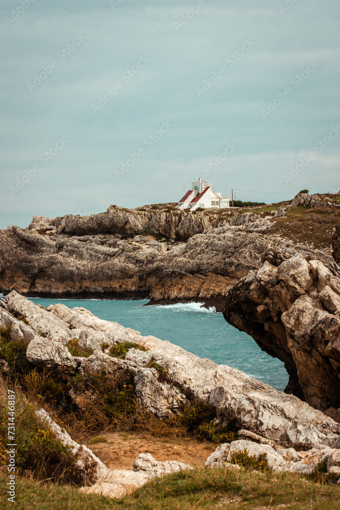 Rocky seashore with residential one-story houses against the blue sky. Amazing calm seascape A nautical wallpaper. Journey to the ocean. Holiday house