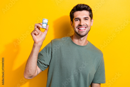 Portrait of cheerful smart guy with stubble wear stylish t-shirt hold mondey get passive income isolated on yellow color background photo