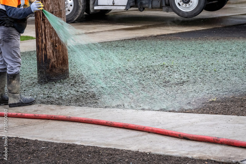 Professional hydroseeding, workman spraying a mix of grass seed and wood pulp from a big hose onto a freshly prepared dirt in a new residential community
