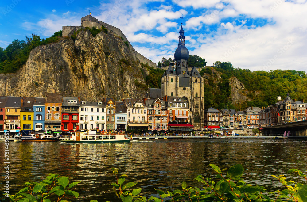 Scenic view from Meuse river of Dinant city with gothic cathedral Collegiate Church of Our Lady, colorful houses and Citadel on hill, Belgium - obrazy, fototapety, plakaty 