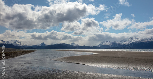 Mud flat tidal outflow at low tide under cumulus clouds on Homer Spit in Homer Alaska United States