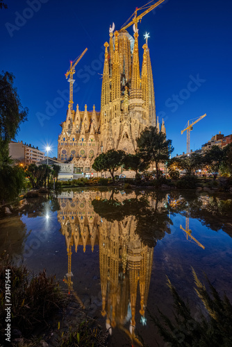 The famous Sagrada Familia in Barcelona at night reflected in a small pond
