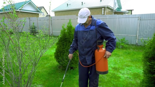 A man works in the garden, spraying weeds from a sprayer