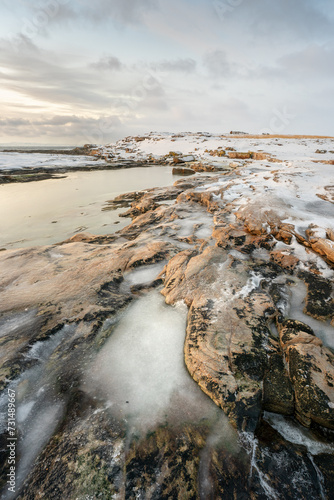 A frozen pool of water on the rock in a winter landscape by the sea, Ekkerøya, Northern Norway photo