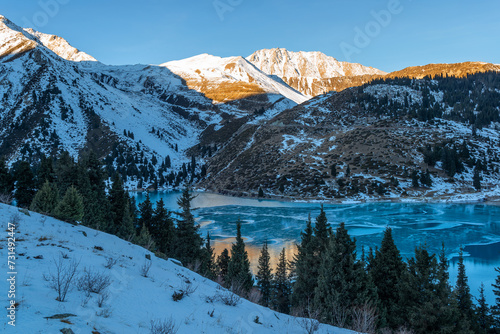 Mountain lake in the vicinity of the Kazakh city of Almaty and snow-covered mountains in the early morning