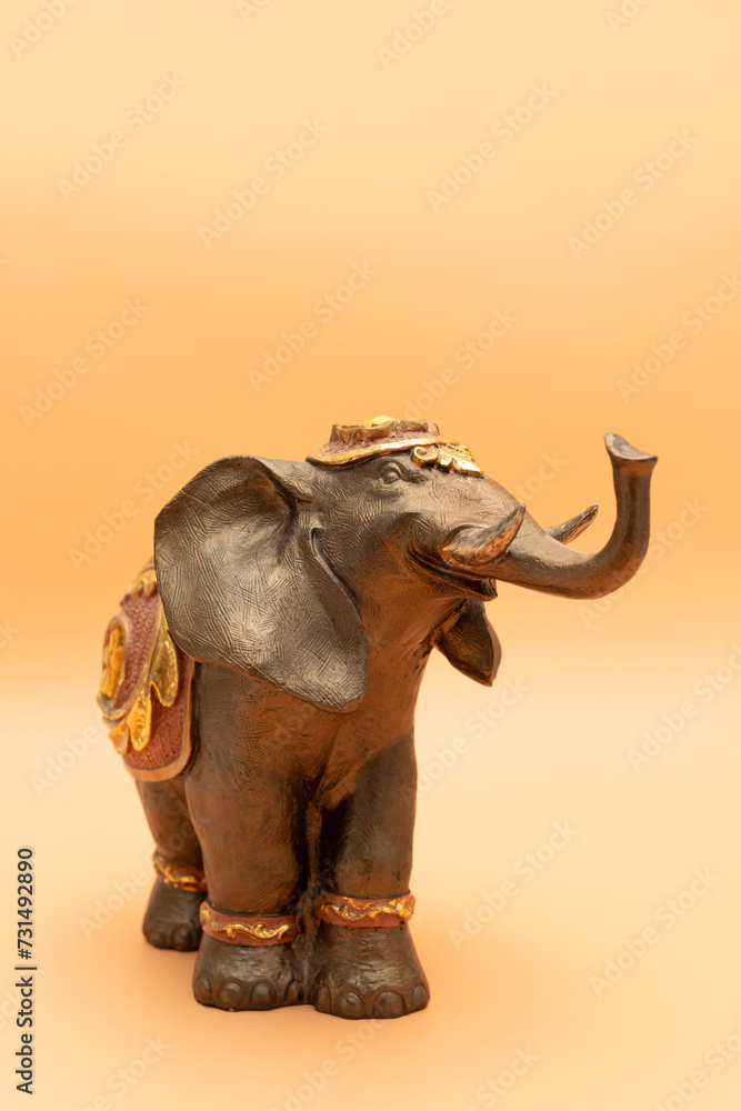 Fototapeta premium Template World Elephant Day. Bronze Decorated Elephant On Peach Yellow Background. Copy Space For Text. Ganesha Chaturthi Holiday. Sacred Symbol In Hindu, Buddhist Religions. Design, Vertical Plane.