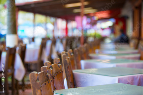 Restaurant in Guatape with old wooden chairs and tables in a row with bokeh effect. Colombia photo