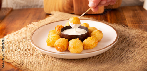 Human hand dipping a Fried breaded cheese bite, easy and delicious homemade snack recipe. Served with dipping sauce.
