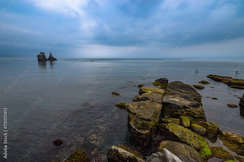 Double Candlestick Island at a distance, beautiful big rocks by the coast, and the weather is cloudy, in Jinshan, New Taipei City, Taiwan.
