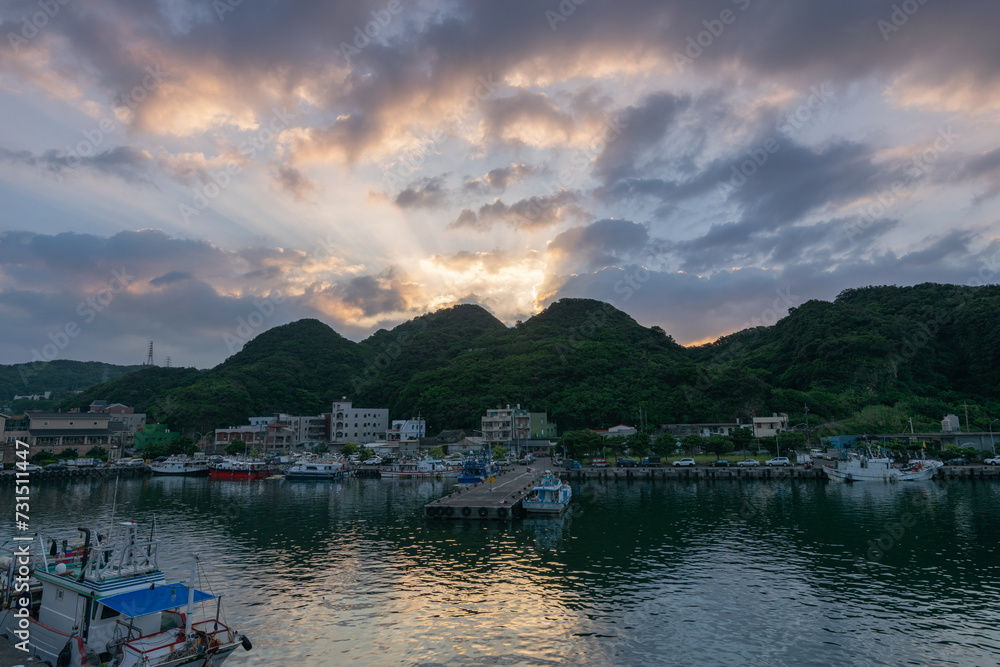 Sunset view of little fish harbor, sunlight go through the mountain and cloud, in New Taipei City, Taiwan.