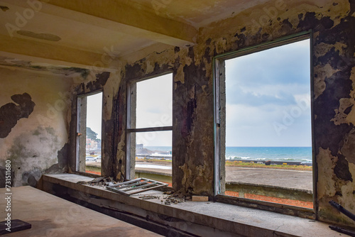 Inside abandoned old factory with three huge windows  and ocean in the front  in Jinguashi  New Taipei City  Taiwan.