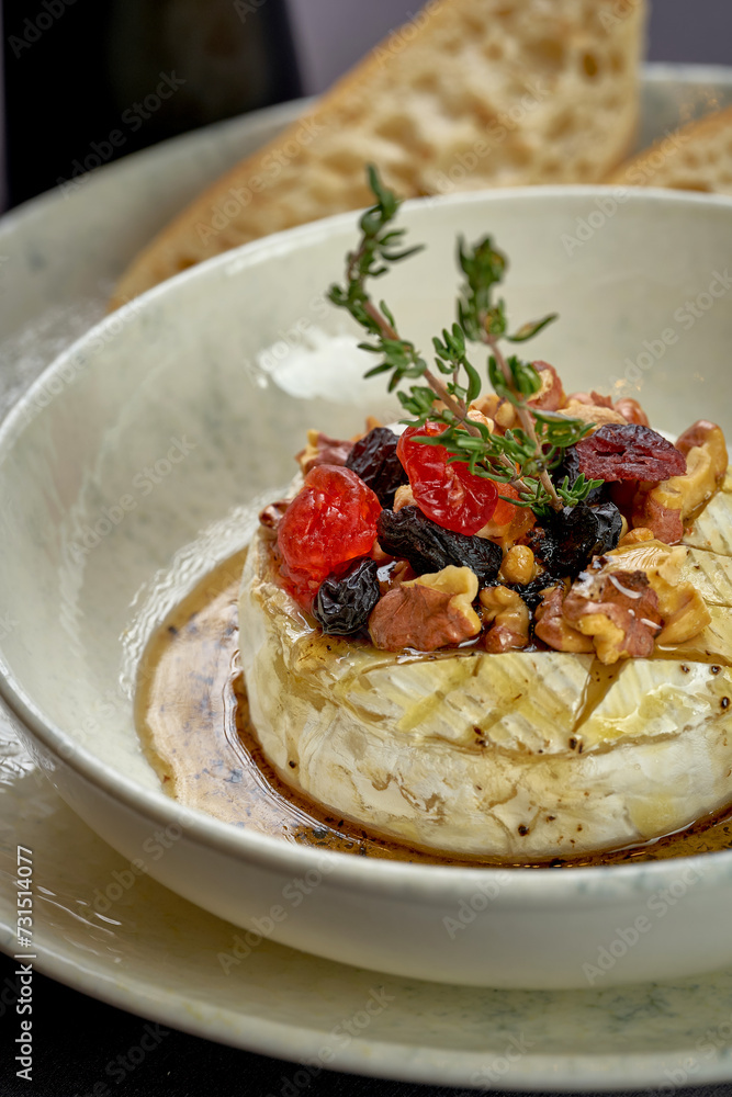 Baked camembert with berries and nuts in a plate. Photo for the menu