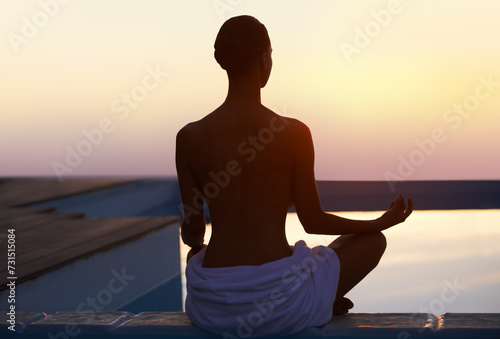 Back, yoga and woman meditate at sunset by swimming pool for healthy body, wellness and zen outdoor on mockup space. Rear view, lotus pose and silhouette of person at twilight to relax, peace or calm