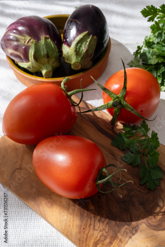 Ripe red Roma tomatoes in bowl with fresh herbs photo