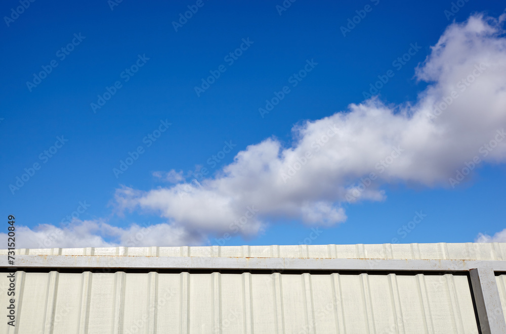 Corrugated steel fence against blue sky. Corrugated metal texture surface or galvanize steel Corrugated steel fence against blue sky. Corrugated metal texture surface or galvanize steel