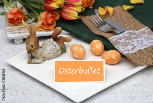 Tischdekoration Zum Osterfest: Teller, Besteck und Osterdekoration mit dem Text Osterbuffet auf einer Tischkarte