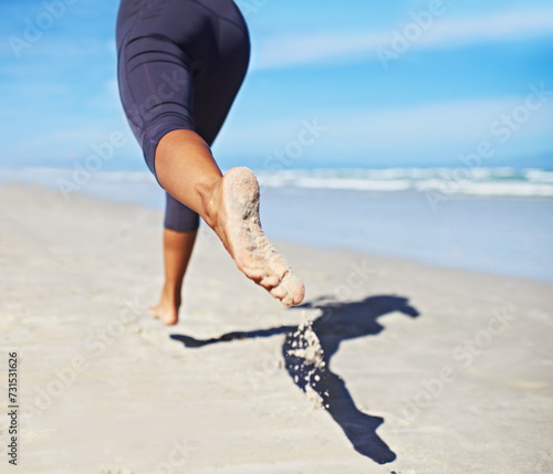 Person, running and feet at beach with exercise, sport and training for marathon by the sea. Workout, fitness and back of a athlete with health and wellness outdoor of runner with cardio in summer