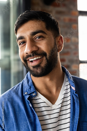 Young Asian man smiles warmly in a casual business office setting photo