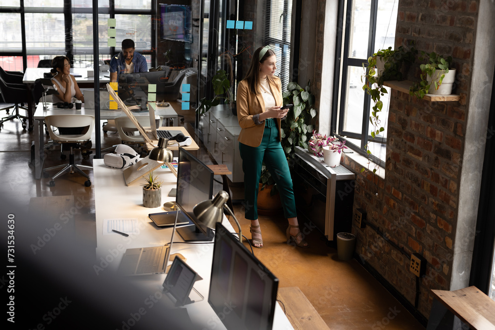 Young Caucasian woman stands in a modern, casual business office Young Caucasian woman stands in a modern, casual business office