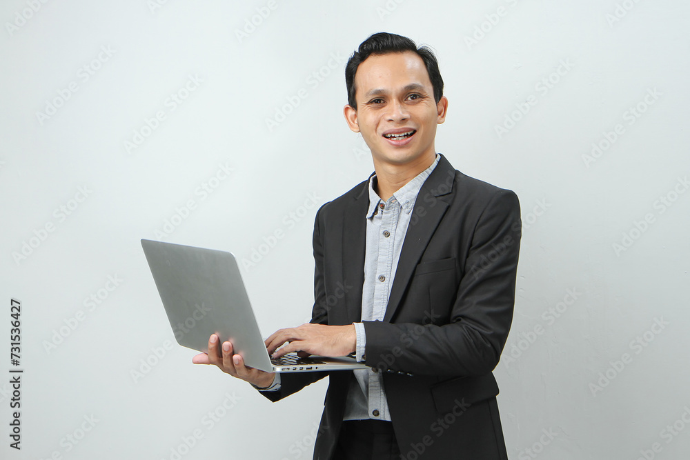 Happy asian indonesian business man in suit holding laptop computer on isolated background Happy asian indonesian business man in suit holding laptop computer on isolated background