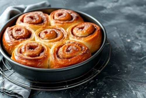 Cane sugar cinnamon rolls in a black ceramic bowl on a round cooling rack Home baked photo