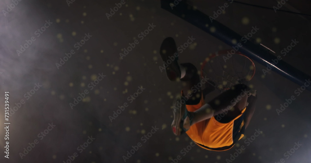 Fototapeta premium Image of particles moving over male basketball player scoring hoop