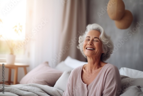 Happy fresh mature middle aged woman stretching in bed waking up alone happy concept, smiling old senior lady awake after healthy sleep sitting in cozy comfortable bedroom interior enjoy good morning. photo