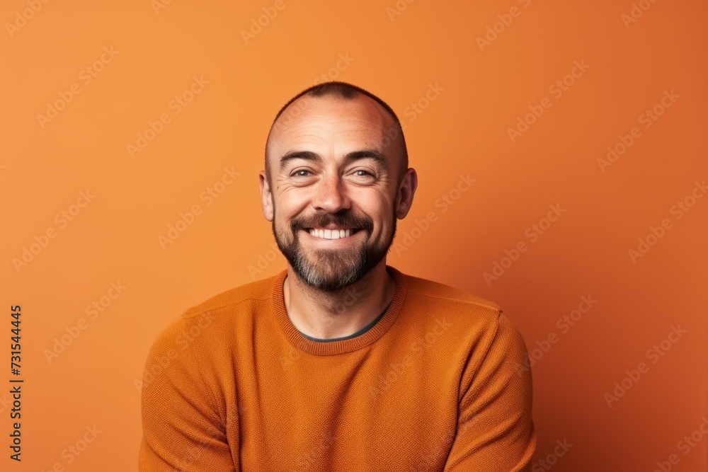 Portrait of a smiling man in orange sweater over orange background
