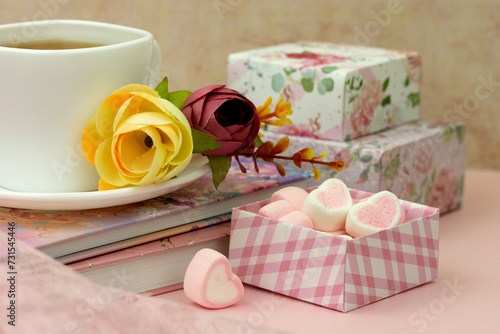 Romantic setting with flowers, a cup of tea, dessert and gifts. Poster for interior. Marshmallow hearts symbolize love.
