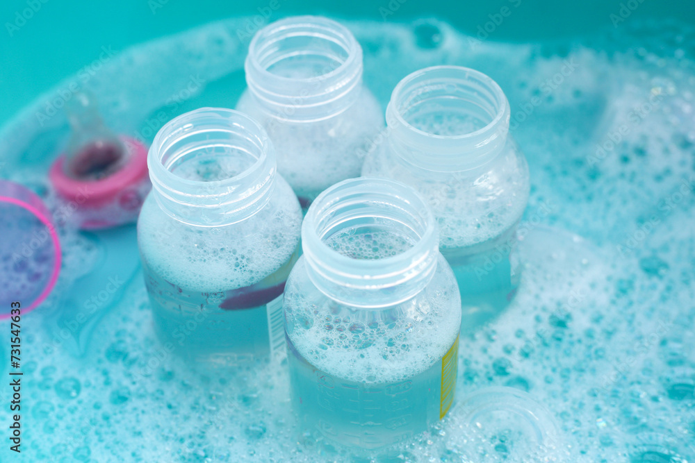 Wash baby bottles in plastic blue basin Wash baby bottles in plastic blue basin