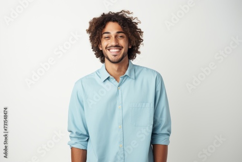 Happy young man with curly hair in a light blue shirt smiling © Iona