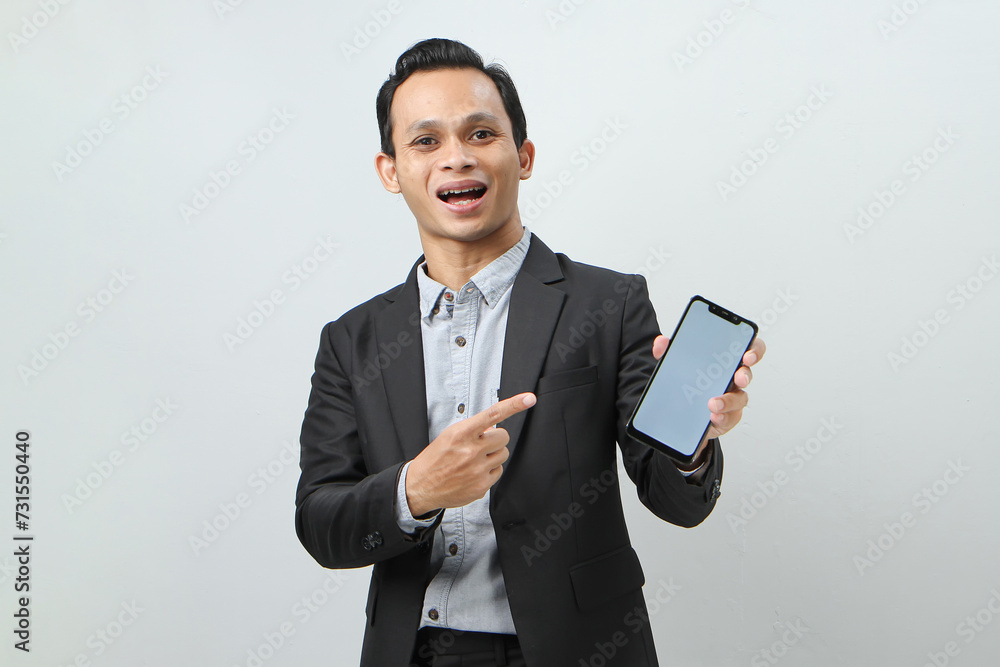 Happy confident asian indonesian business man in suit showing blank smartphone screen on isolated background Happy confident asian indonesian business man in suit showing blank smartphone screen on isolated background