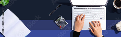 Woman using a laptop computer with a piggy bank and a calculator