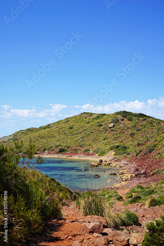 Natural landscape of Playa de Cavalleria (Mercadal) in Minorca beach with clear blue sky and rocky seashore- Menorca, Spain