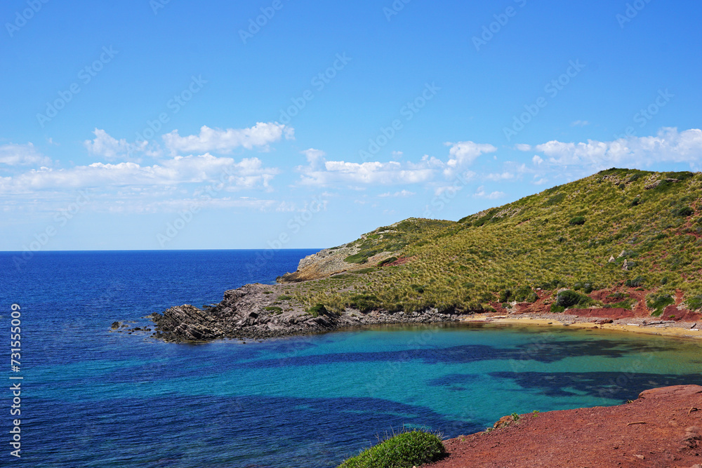 Natural landscape of Playa de Cavalleria (Mercadal) in Minorca beach with clear blue sky and rocky seashore- Menorca, Spain
