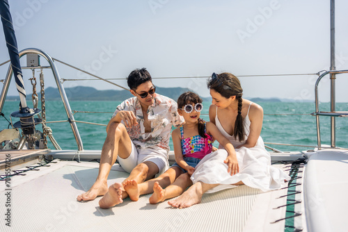 Asian happy family sitting on deck of yacht while yachting outdoor. © Kawee