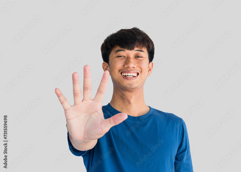 Portrait of a happy young Asian man wearing a blue t-shirt with five fingers extended in front of him apart on a gray background. Portrait of a happy young Asian man wearing a blue t-shirt with five fingers extended in front of him apart on a gray background.