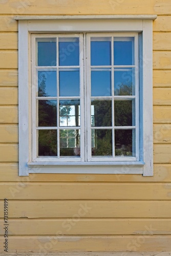 An old wooden white framed window on a yellow painted wall.