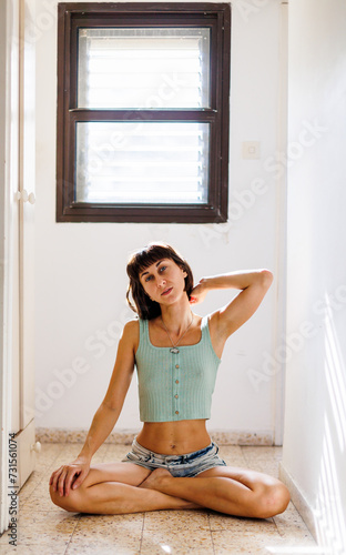 Portrait of a young girl with black short hair in a bright room. Close-up of a carefree young woman.