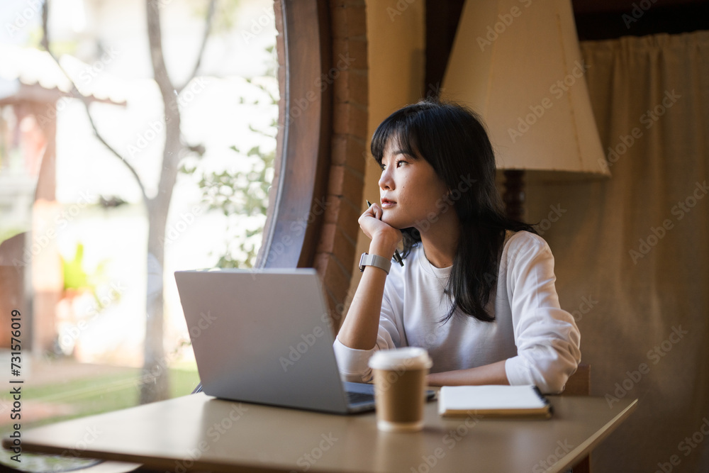 Pensive young adult woman working on a laptop in a cozy home setting, deep in thought.. Pensive young adult woman working on a laptop in a cozy home setting, deep in thought..