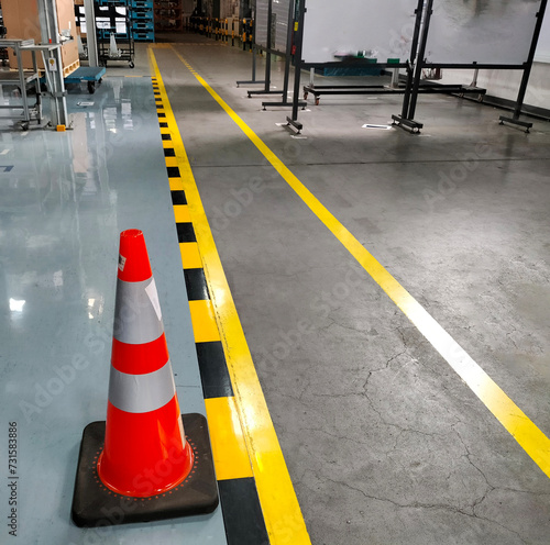 Industrial building corridor painted yellow between parallel yellow lines on abstract cement background. There are red cones located to ensure safety in pedestrian traffic. photo