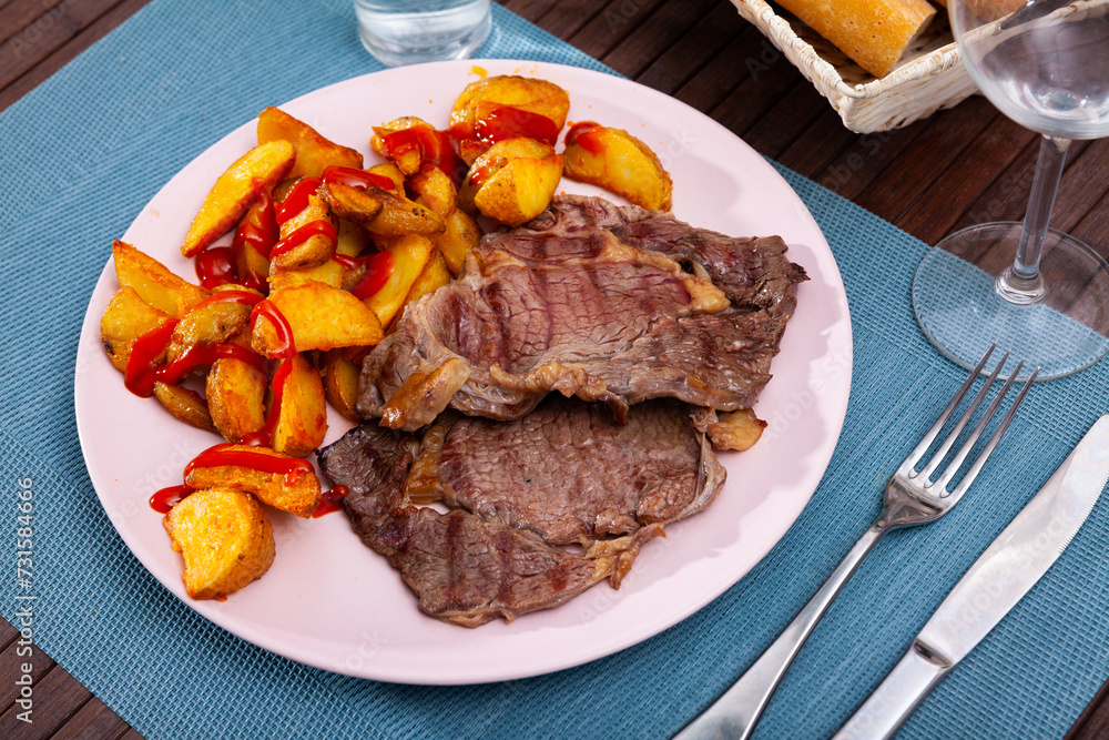 Tasty homemade baked beef fillet served with fried potato wedges and ketchup