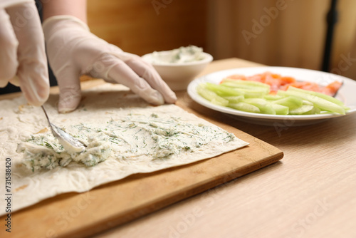 A layer of cheese mass is applied to pita bread. Preparation of pita bread roll.