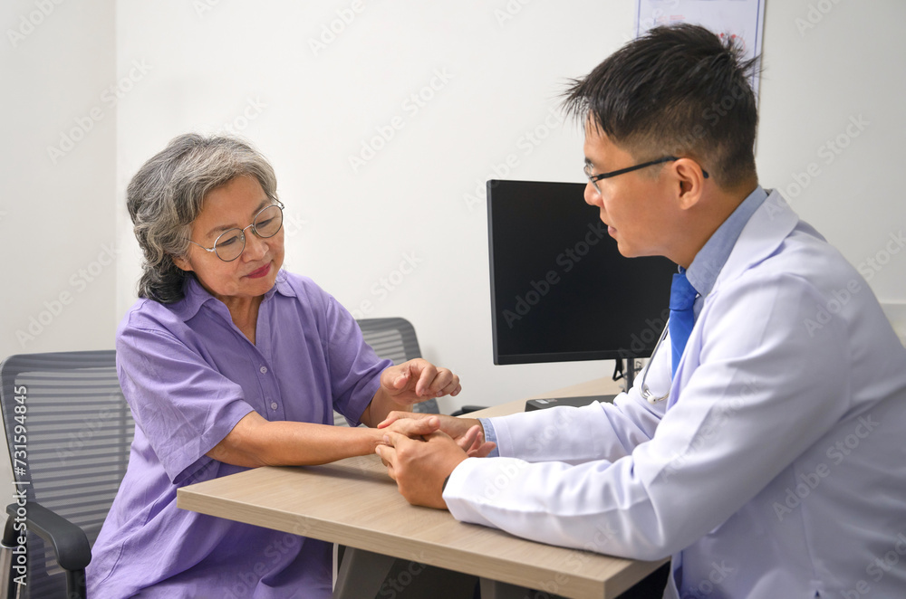asian senior woman being wrist examined by professional doctor due to joint pain in examine room,concept of elderly life,health care and medical