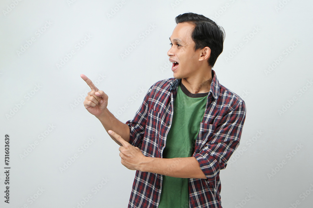 Happy asian indonesian man with pointing finger gesture on isolated background Happy asian indonesian man with pointing finger gesture on isolated background