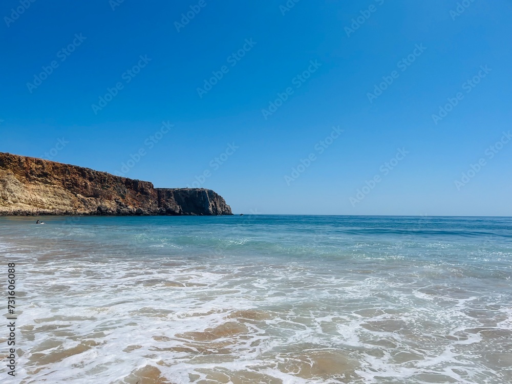 Rocky coast of the ocean bay, clear blue sky, ocean horizon, rocks