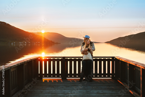 Valentines Day celebration: Romantic couple in love man and woman hugging on pier enjoying sunset view. Dating outdoor lovers relationship family travel lifestyle, lake and mountains landscape photo