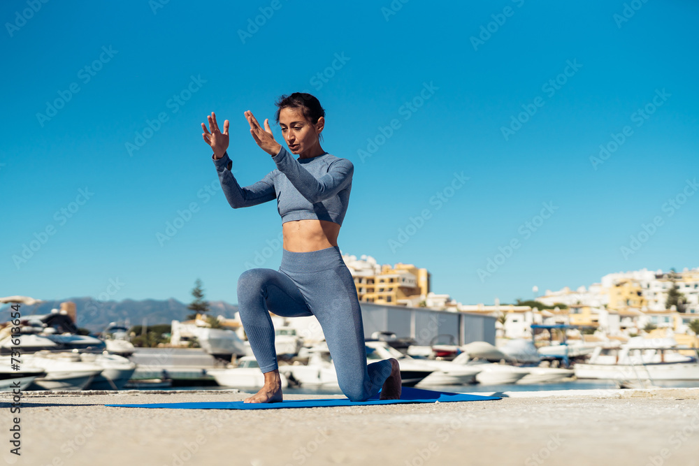 Young beautiful woman exercising on the pier during sports training. there is space for text. fitness trainer shows an exercise for his blog