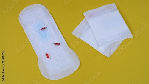 A creative shot of painful mensuration with a sanitary pad and falling board pins on a yellow background - menstruation cramps  heavy bleeding. Awareness about the Dysmenorrhea - the painful menstr... photo