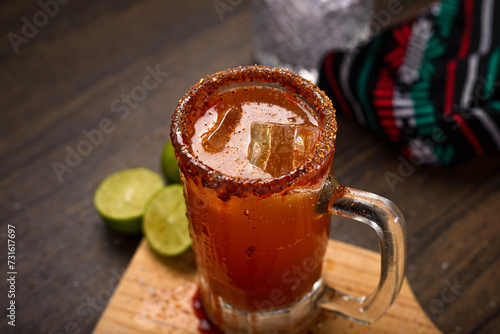 Michelada, typical mexican cocktail on a wooden table. Beer cocktail. photo